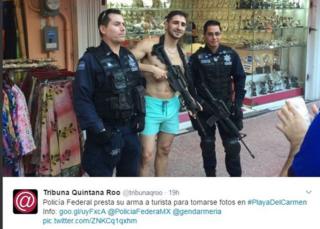 A photo tweeted by news site Tribuna Quintana Roo shows a tourist with a weapon posing with two Mexican federal police officers