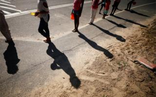 Children queue for food at a school feeding scheme during a nationwide lockdown.