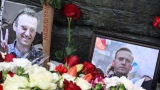 Photographs showing late Russian opposition leader Alexei Navalnyare are displayed next to flowers at the monument to the victims of political repressions in Moscow on February 17, 2024,