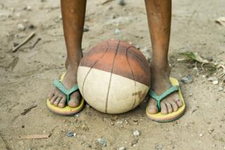 A basketball at a young man's feet