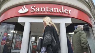 A woman walks past Santander bank in the UK