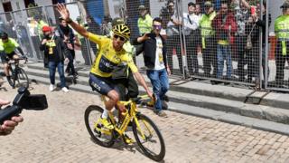 Colombia's Tour de France winner Egan Bernal waves as he rides his bike upon his arrival in his hometown Zipaquira, Cundinamarca, Colombia