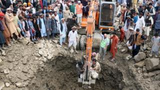 A crane lifts a victim who died in the floods in Charikar