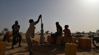 children dey try pump wata from borehole.