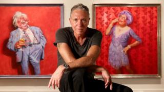 Билл Лик позирует перед двумя картинами австралийского комика Барри Хамфриса