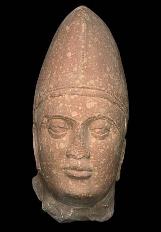 A sculpture of a Kushan king made of spotted red sandstone