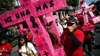 Women carry pink crosses during the 