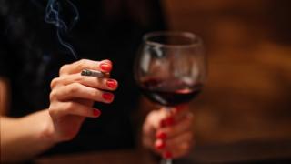 Woman holding cigarette and glass of wine