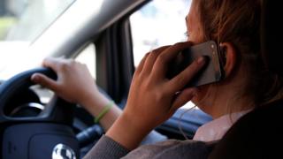 Женщина за рулем на своем мобильном телефоне