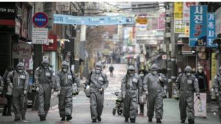 workers in South Korea disinfect a street