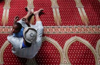 A Muslim faithful holds his son as they perform Eid al-Fitr prayers, marking the end of the holy fasting month of Ramadan, inside a mosque closed amid concerns about the spread of the coronavirus disease (COVID-19), in Nairobi, Kenya, May 24, 2020.
