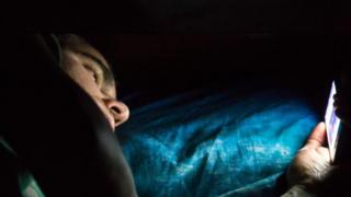 Homem ao celular na cama