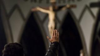 Hombre frente a Cristo levantando la mano
