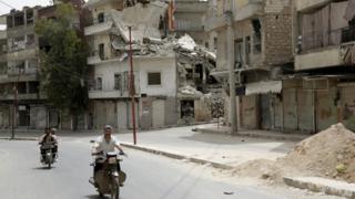 Men ride motorbikes along a street in the north-western city of Ariha, after a coalition of insurgent groups seized the area in Idlib province