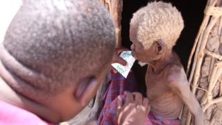 Mwandishi wa habari wa BBC Roncliffe Odit akimpatia maziwa mzee Lomoni
