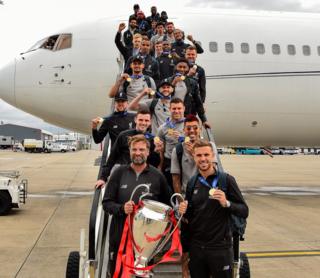 Jurgen Klopp and players with trophy as they come out of plane