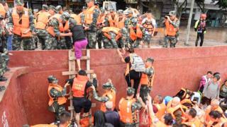 Rescuers help evacuated villagers get off boats onto land in Sichuan (18 August)