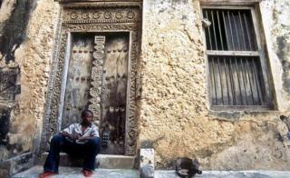 A boy sits in front of a house in Lamu town.