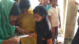 বাংলাদেশের একটি গ্রামে পরীক্ষার ফল দেখছেন শিশু শিক্ষার্থীরা।