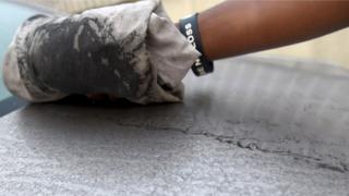 An attendant wipes clean black soot covering a car