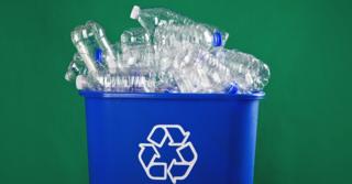 Botellas de plástico en un cubo con el símbolo de reciclaje.