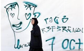 Romanian Orthodox nun passes graffiti symbolizing the crying face of a member of the LGBT community on October 5