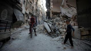 Syrians walk through the rubble