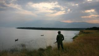 Конголезский смотритель парка просматривает озеро Эдвардс 21 июля 2006 года в национальном парке Вирунга в восточной части Демократической Республики Конго.