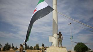 Combatientes sirios alzan bandera en la ciudad de Ayn al-Arus.