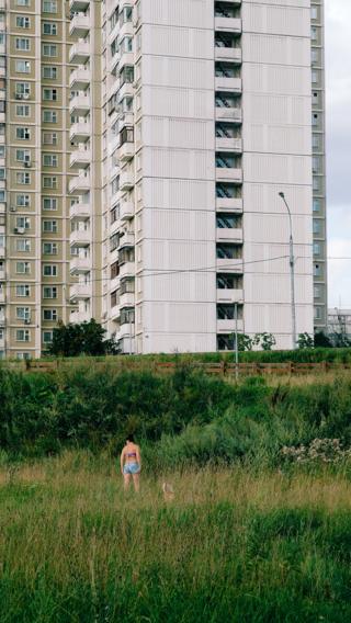 Женщина стоит на фоне многоэтажного дома