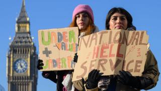 Nurses and supporters hold placards as they gather to demonstrate outside St Thomas' hospital in Westminster, London, on 15 December 2022