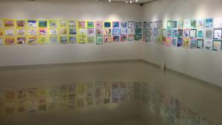 En una exposición de dibujos, reflejos en el piso, reflejos en todos lados.