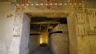 The inside of the tomb with colourful paintings surrounding it on the outside.