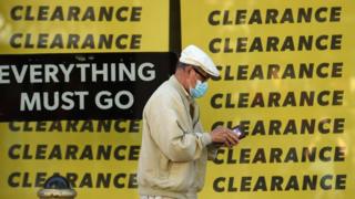 A man wearing a protective face mask walks past a shop advertising a clearance sale in York.