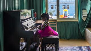 Girl in traditional dress plays the piano