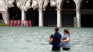 Couple walking on Piazza San Marco flooded in Venice on October 29, 2018