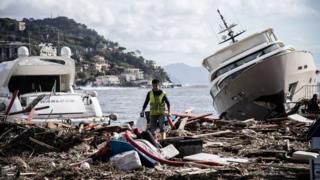   A man crosses garbage between two yachts after a storm hit the harbor and destroyed part of the dam during the last night of October 30, 2018 