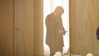 Boris Johnson looking at his phone during his recent visit to Chile