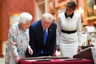 La Reina Isabel II mostrando artículos en exhibición a Donald y Melania Trump.