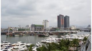 Luxury yachts sit docked at the Visun Royal Yacht Club in front of fishing boats and residential developments in the Sanya Bay district of Sanya, Hainan Province, China, on Monday, April 7, 2014.