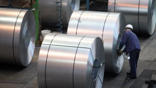 A worker inspects steel in a factory