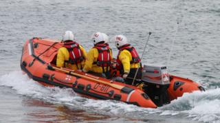 D-Class rigid RNLI inshore lifeboat at Pwllheli, Gwynedd, on the water with crew wearing full safety equipment 