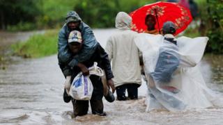 Residents wade through flood waters after a river burst its banks in heavy rainfall in Kitengela, near Nairobi, Kenya.