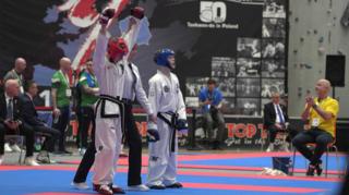 A martial arts competition with a young man with his arms in the air