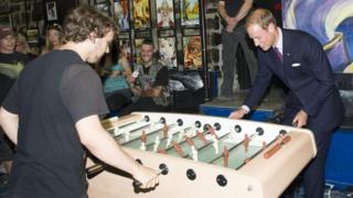 Prince William, the Duke of Cambridge plays a game of foosball with Steven, 21, as he and the Duchess visit a shelter for homeless teenagers in Quebec City