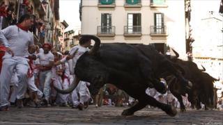 A bull loses its balance during the third day of the San Fermin running-of-the-bulls in Pamplona, Spain