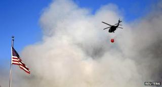 A helicopter hovers above a buring fire