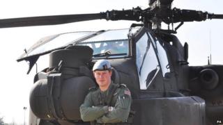 Prince Harry in front of an Apache helicopter