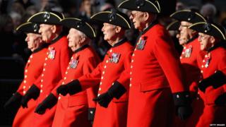 Group of Chelsea Pensioners march from right to left.