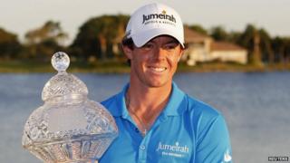 Rory McIlroy celebrates with trophy after becoming top golfer in the world.
